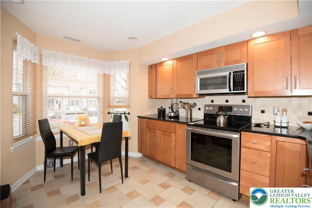 112 Freedom Court Bethlehem, PA 18020 - Photo 2 of 16 a kitchen with stainless steel appliances granite countertop a stove top oven a sink dishwasher a dining table and chairs with wooden floor