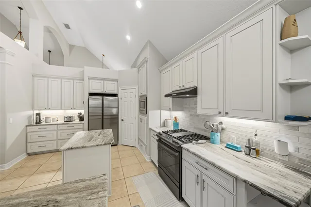 a kitchen with granite countertop a sink stove refrigerator and cabinets
