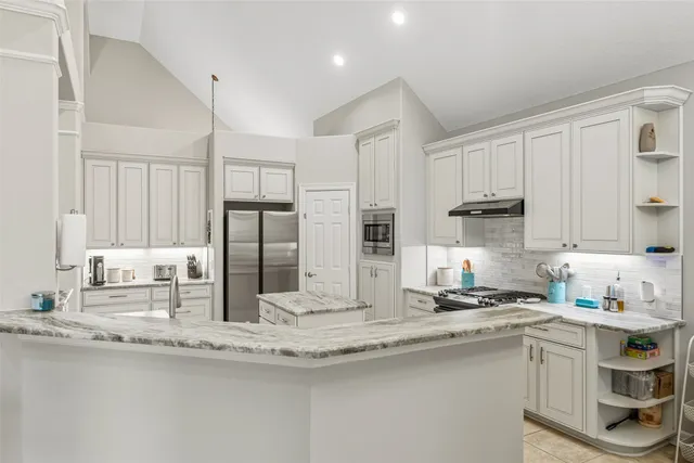 a kitchen with stainless steel appliances granite countertop a sink refrigerator and cabinets