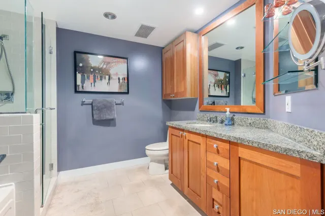 a bathroom with a granite countertop sink mirror vanity and toilet