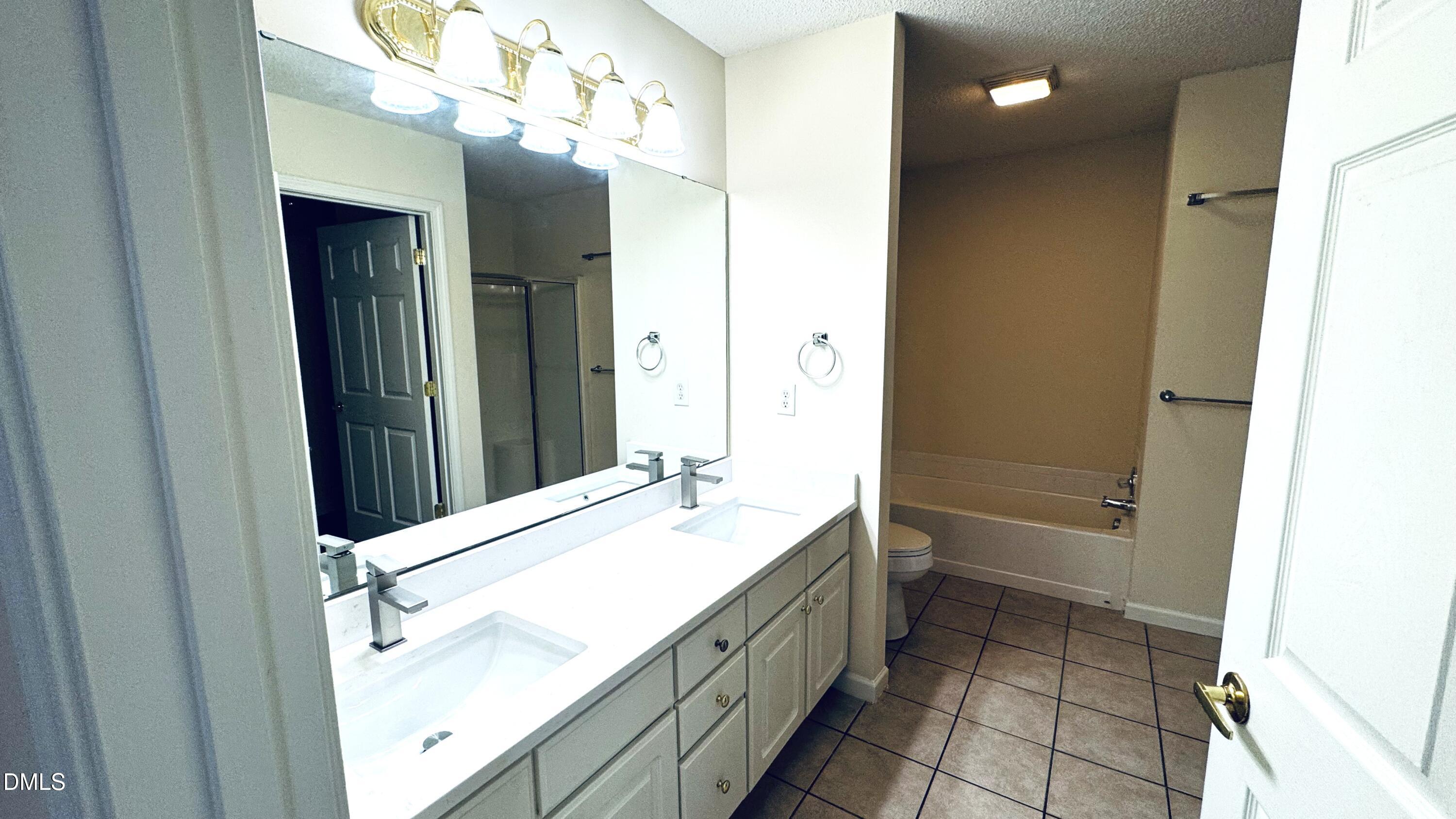 11320 Clubhaven Place, Unit 103 Raleigh, NC 27617 - Photo 9 of 13 a bathroom with a double vanity sink a toilet and a mirror