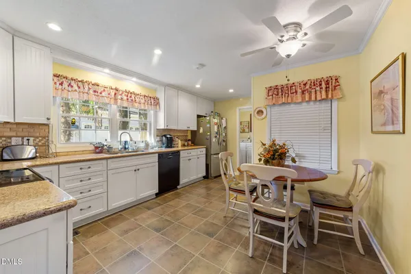 a kitchen with a dining table chairs and white cabinets
