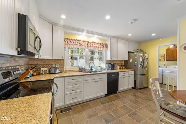 a kitchen that has a lot of cabinets a sink and appliances in it