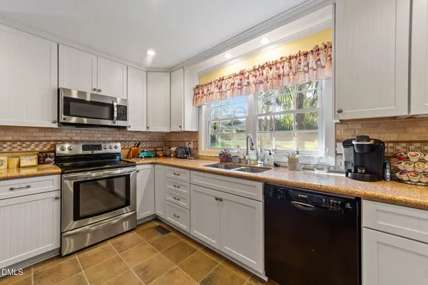a kitchen with granite countertop a stove top oven sink and cabinets