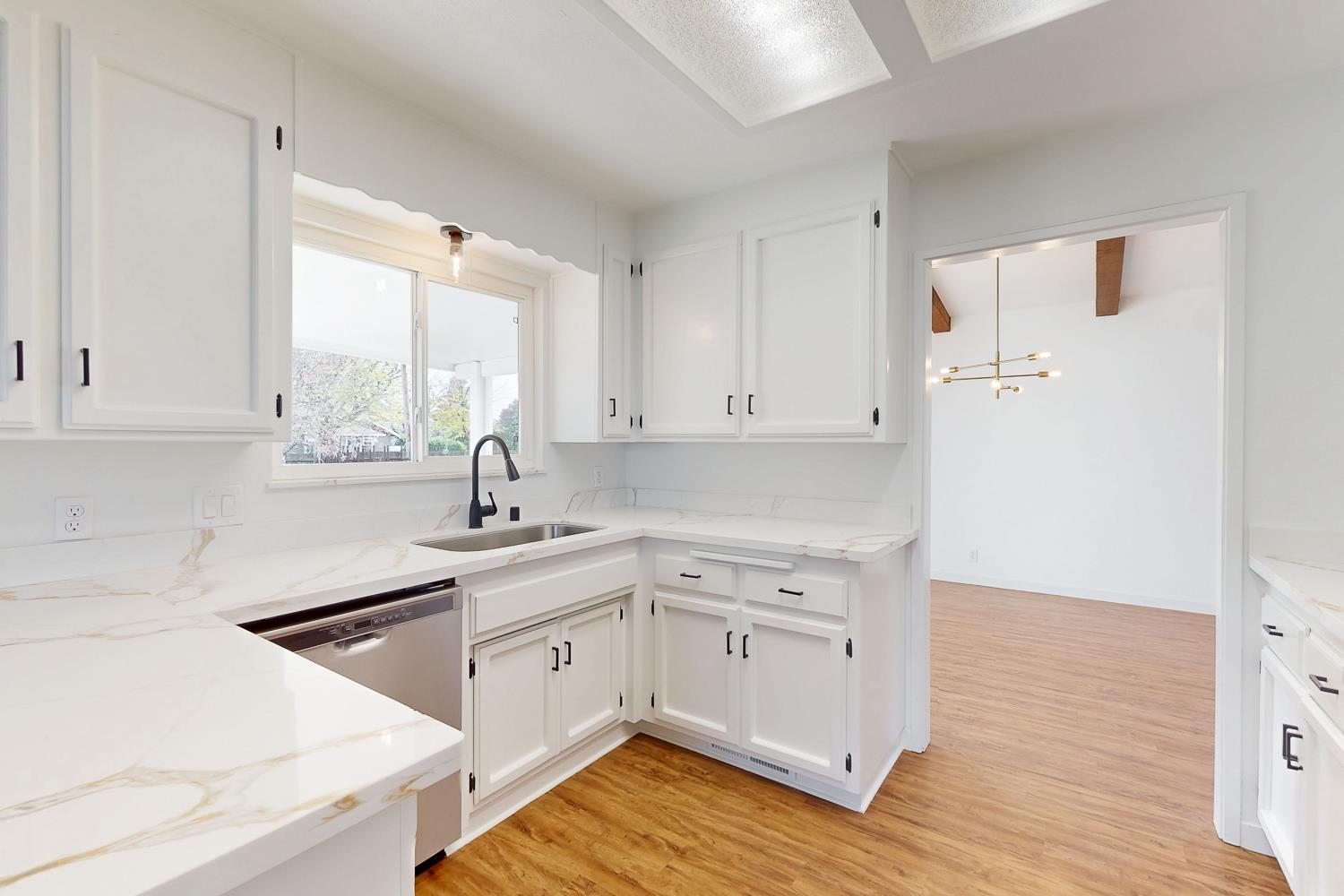 7830 Griffith Lane Sutter, CA 95982 - Photo 25 of 69 a kitchen with a sink dishwasher a stove and white cabinets with wooden floor