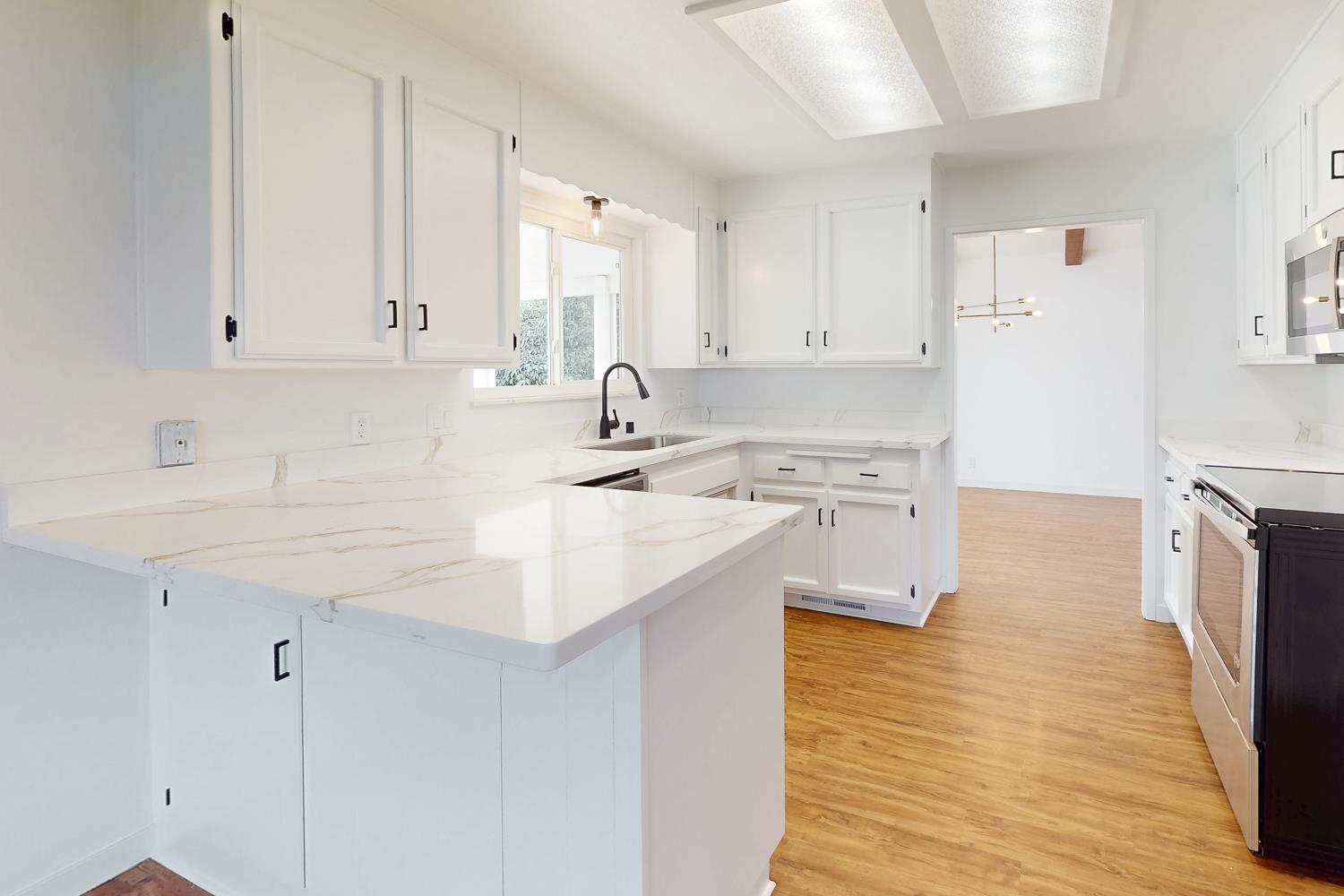 7830 Griffith Lane Sutter, CA 95982 - Photo 26 of 69 a kitchen with stainless steel appliances granite countertop a sink a stove a refrigerator and white cabinets with wooden floor