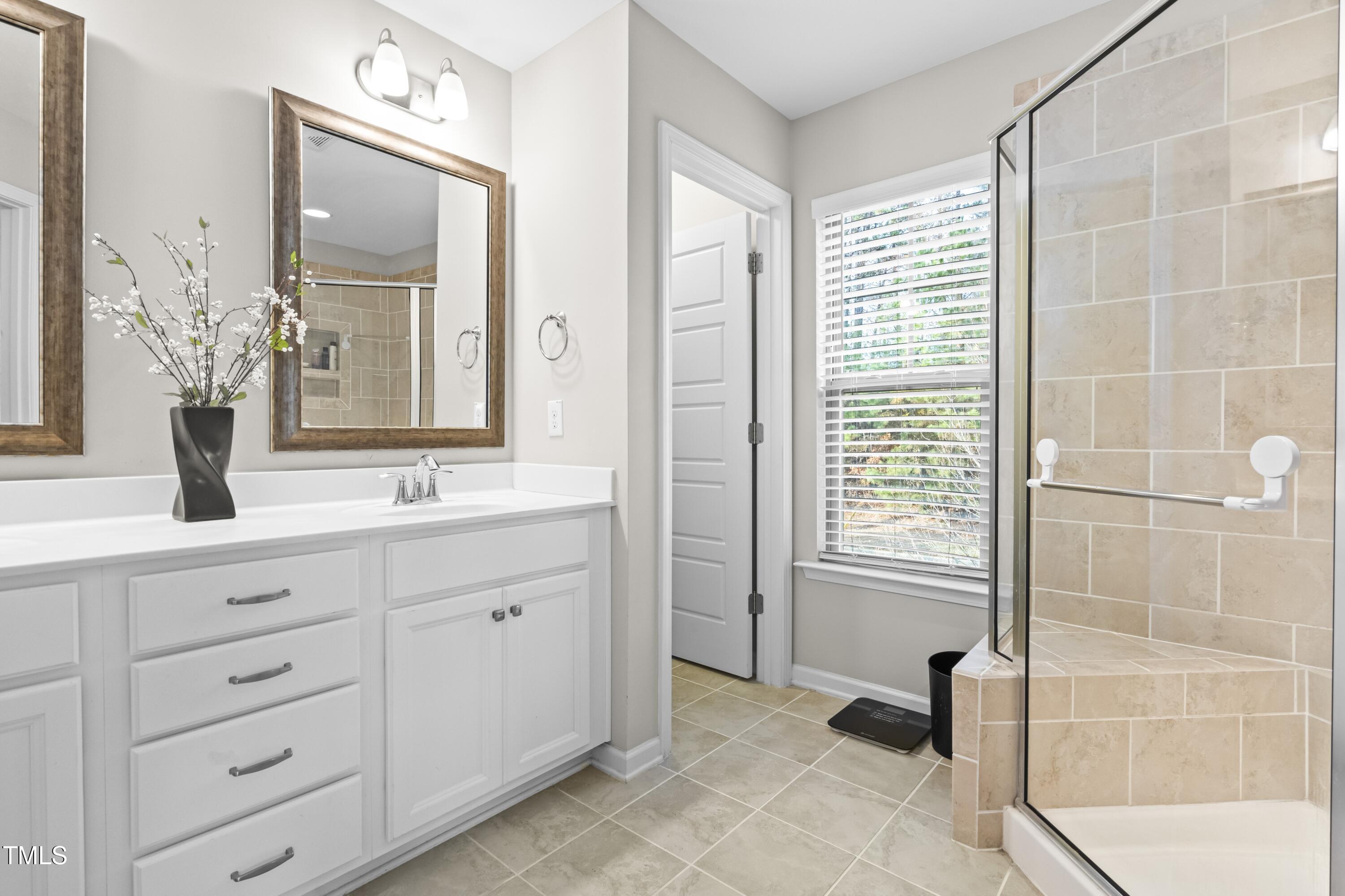 1004 Metropolitan Drive Durham, NC 27713 - Photo 12 of 28 a bathroom with a double vanity sink a mirror and a bathtub
