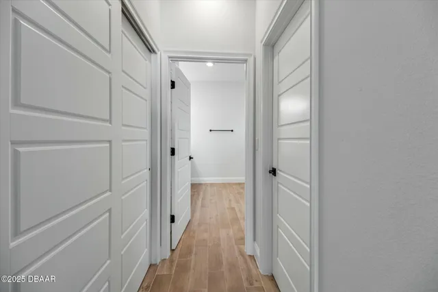 a view of a hallway with wooden floor and closet area
