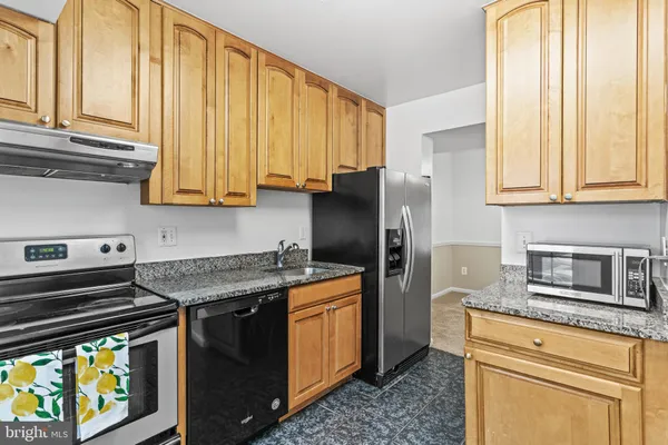 a kitchen with stainless steel appliances granite countertop a refrigerator a stove and a sink