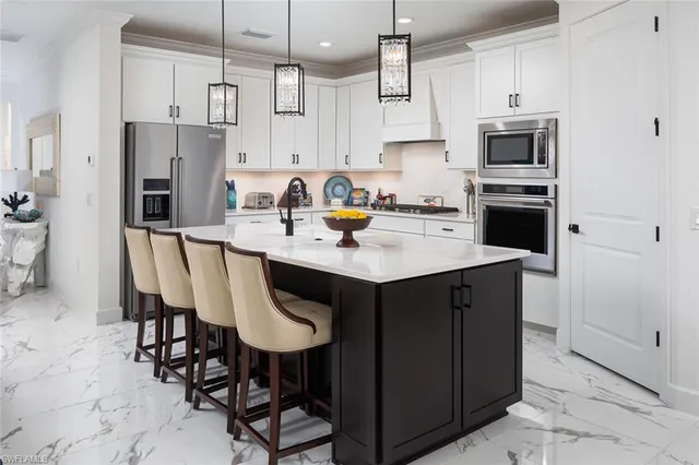 a kitchen with stainless steel appliances granite countertop a stove a refrigerator a sink a dining table and chairs