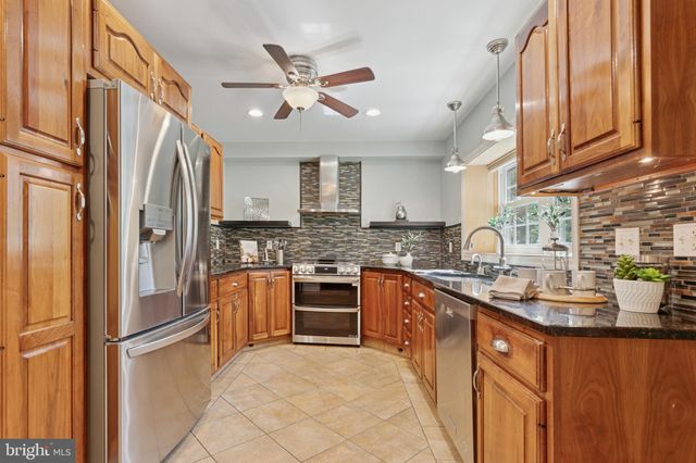 a kitchen with stainless steel appliances granite countertop a refrigerator a sink dishwasher a stove and a refrigerator with wooden floor