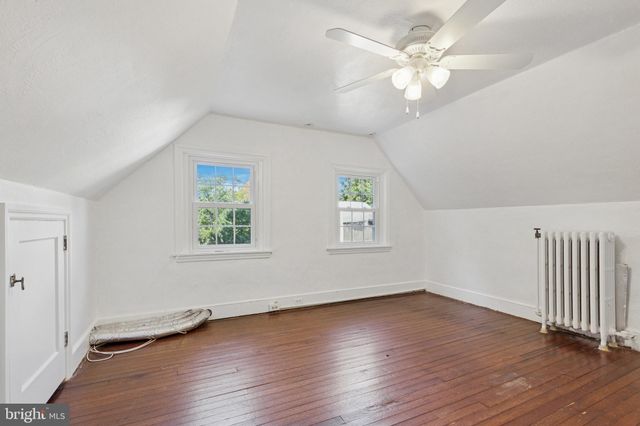 an empty room with wooden floor chandelier fan and windows