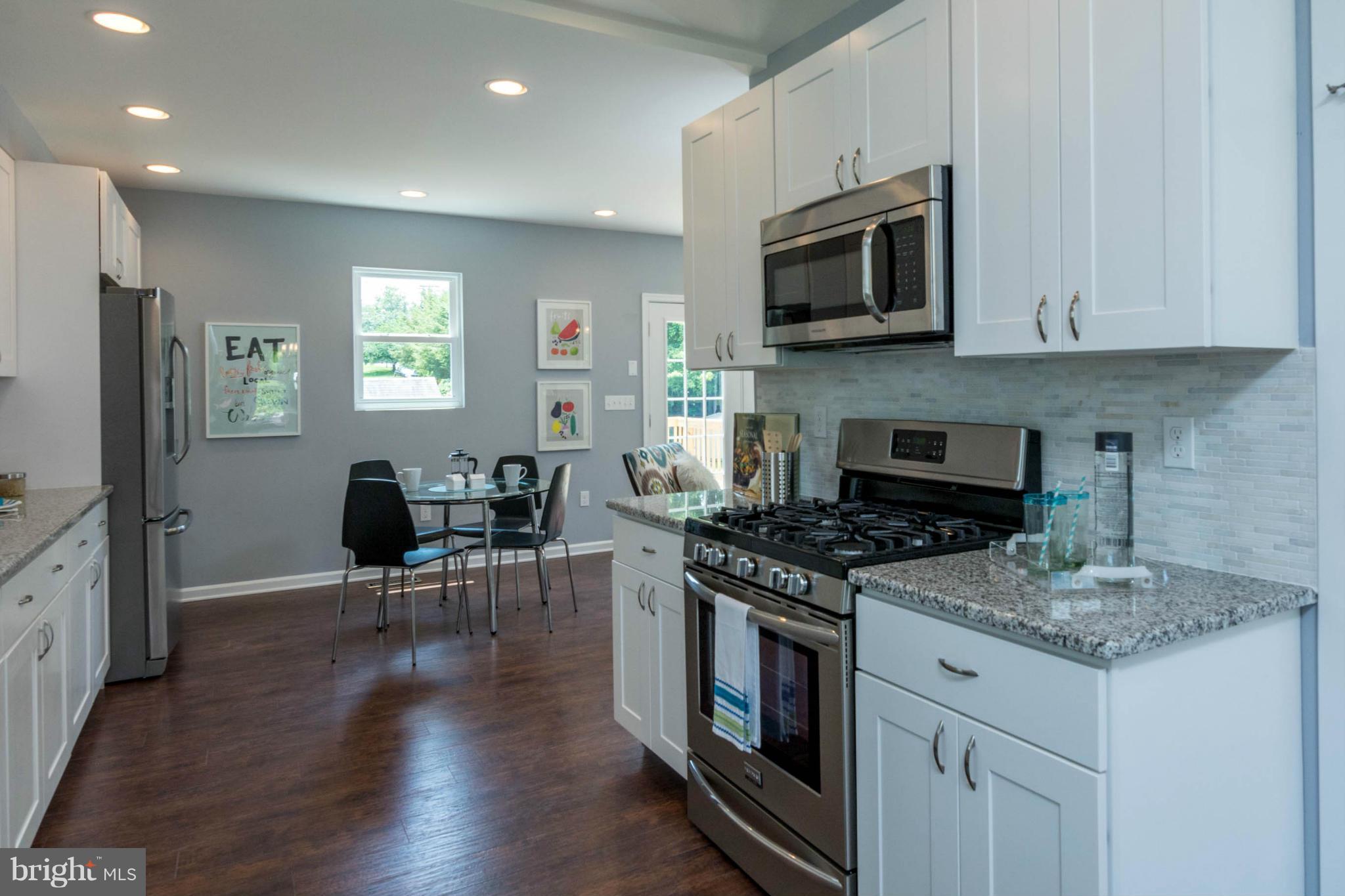 315 East Maple Road Linthicum Heights, MD 21090 - Photo 16 of 30 a kitchen with stainless steel appliances granite countertop a stove top oven a sink dishwasher a dining table and chairs with wooden floor