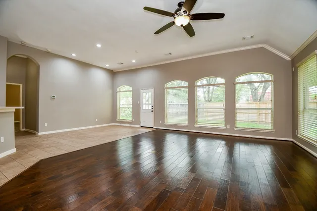 a view of an empty room with wooden floor and a window