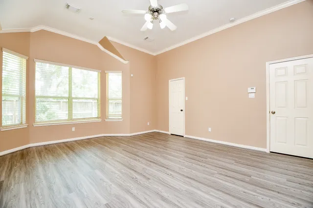 a view of an empty room with wooden floor and a window