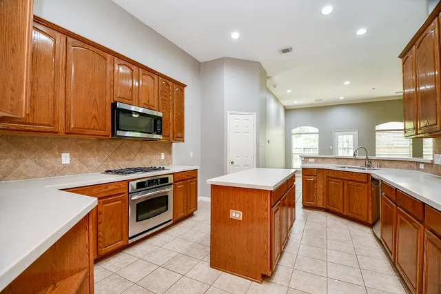 a large kitchen with stainless steel appliances granite countertop a sink counter space cabinets and a large window