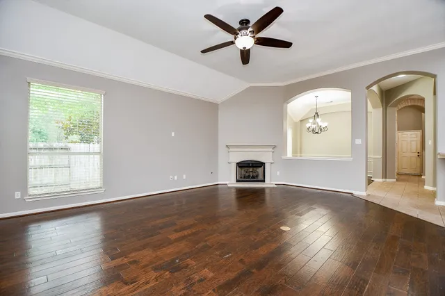 an empty room with wooden floor fireplace and windows