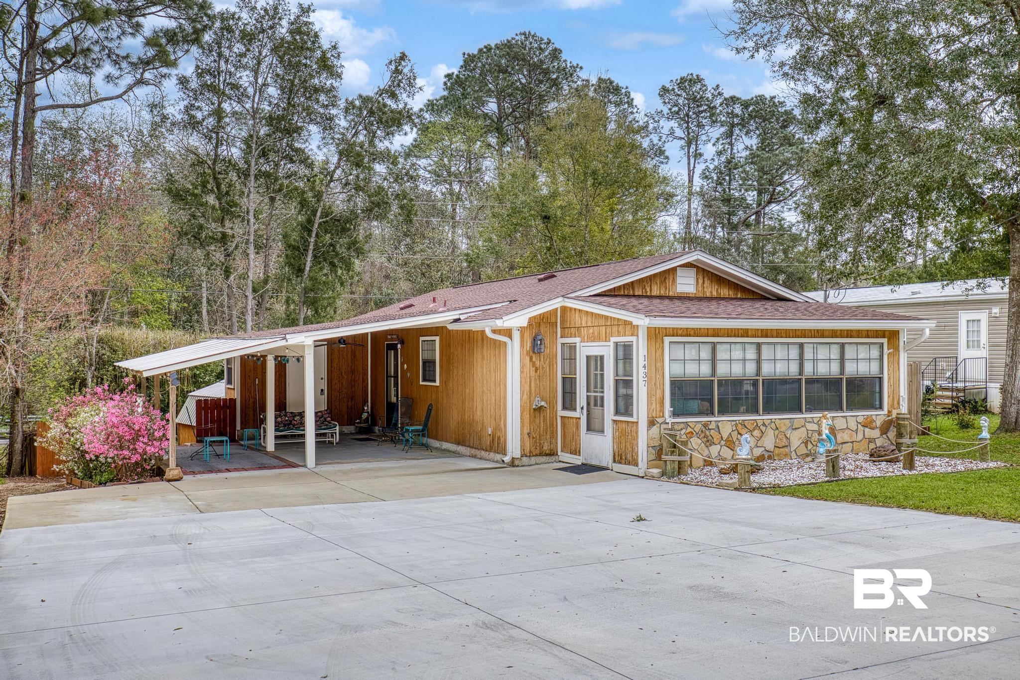 1437 Rio Circle Lillian, AL 36549 - Photo 26 of 46 View of front facade featuring an attached carport, driveway, roof with shingles, and stone siding