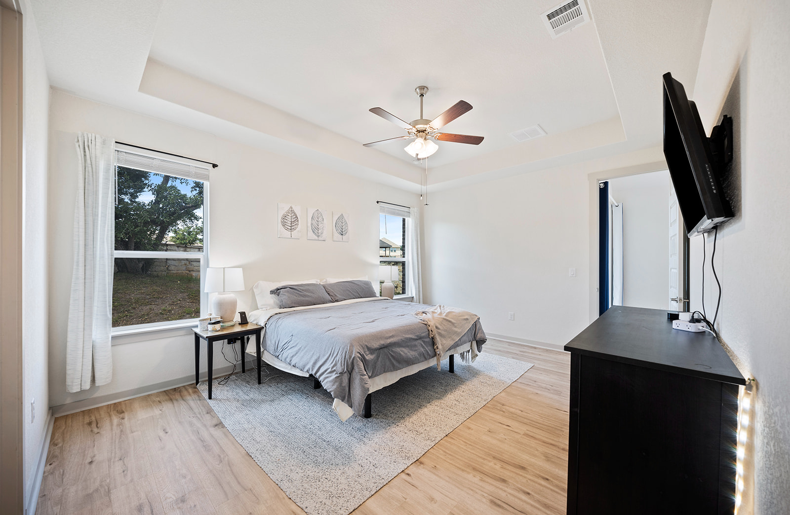 900 Balsora Cove Georgetown, TX 78628 - Photo 11 of 39 Relax in a generously proportioned sleeping area, featuring light wood-style flooring and a sophisticated tray ceiling.
