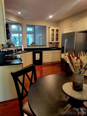a kitchen with stainless steel appliances granite countertop wooden floor dining table and chairs