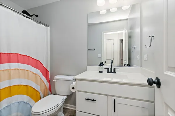 a bathroom with a sink a toilet a mirror and shower curtain
