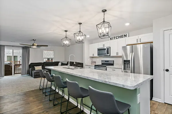 a kitchen with granite countertop a table chairs stove refrigerator and microwave