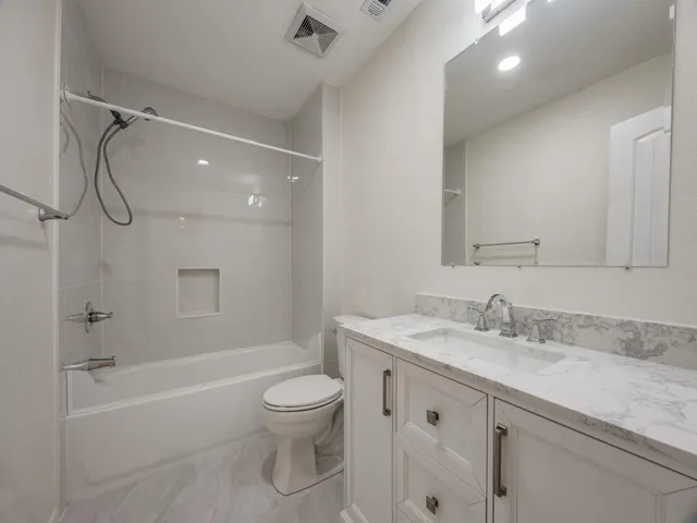 a bathroom with a granite countertop sink a toilet and shower
