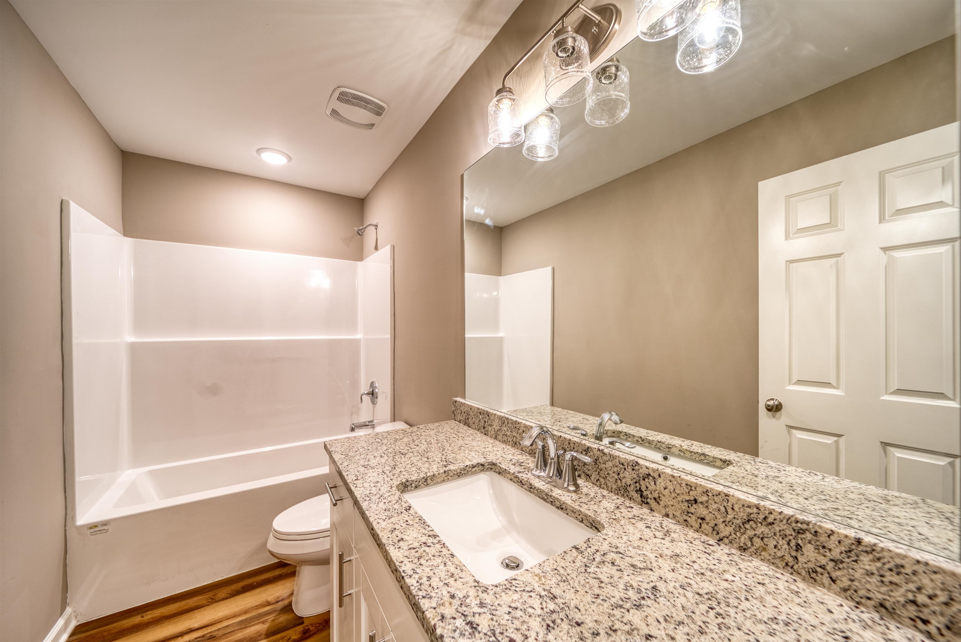 109 Walnut Ridge Ripley, TN 38063 - Photo 22 of 39 a bathroom with a granite countertop sink toilet a large mirror a bathtub and shower