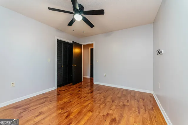 an empty room with wooden floor and ceiling fan