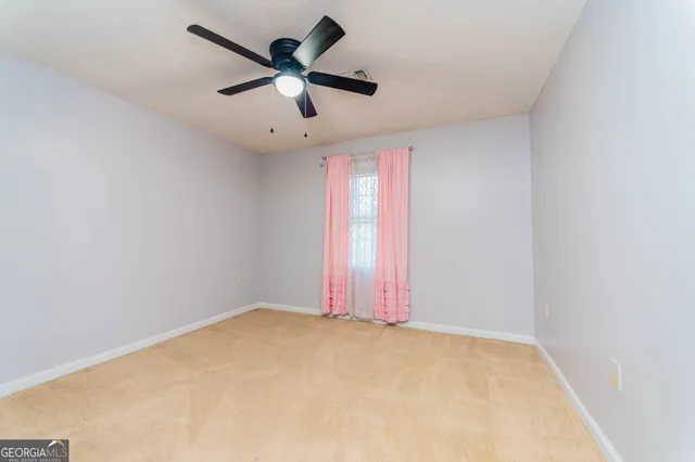 an empty room with a window and a fan