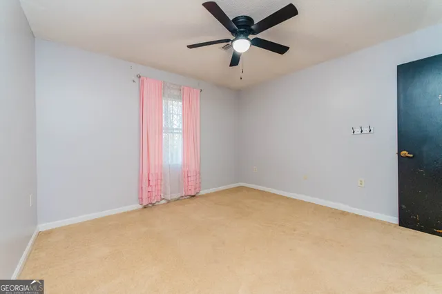 an empty room with a window and a fan
