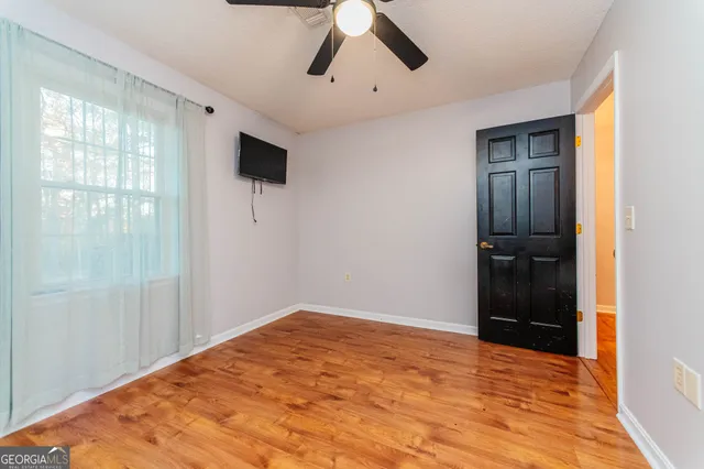 a view of empty room with wooden floor and ceiling fan