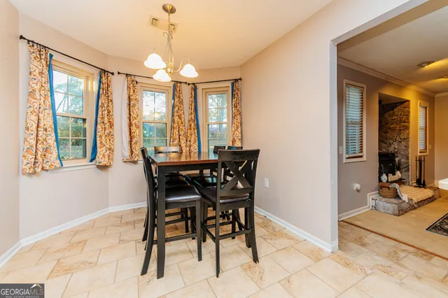 a dining room with chandelier and wooden floor