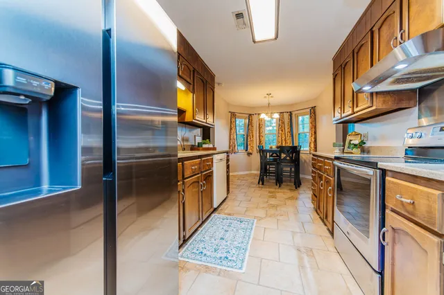 a kitchen with stainless steel appliances kitchen island granite countertop a refrigerator and cabinets