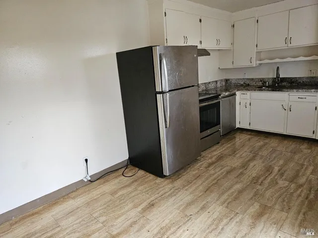 a kitchen with granite countertop a refrigerator and a stove top oven