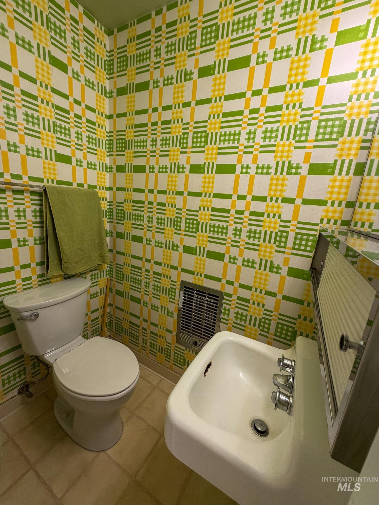 1924 H Street Rupert, ID 83350 - Photo 4 of 13 Bathroom featuring plaid patterned wallpaper, a white pedestal sink with chrome fixtures, and a coordinating white toilet