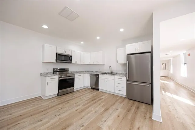 a kitchen with a sink a refrigerator a stove top oven and wooden floor