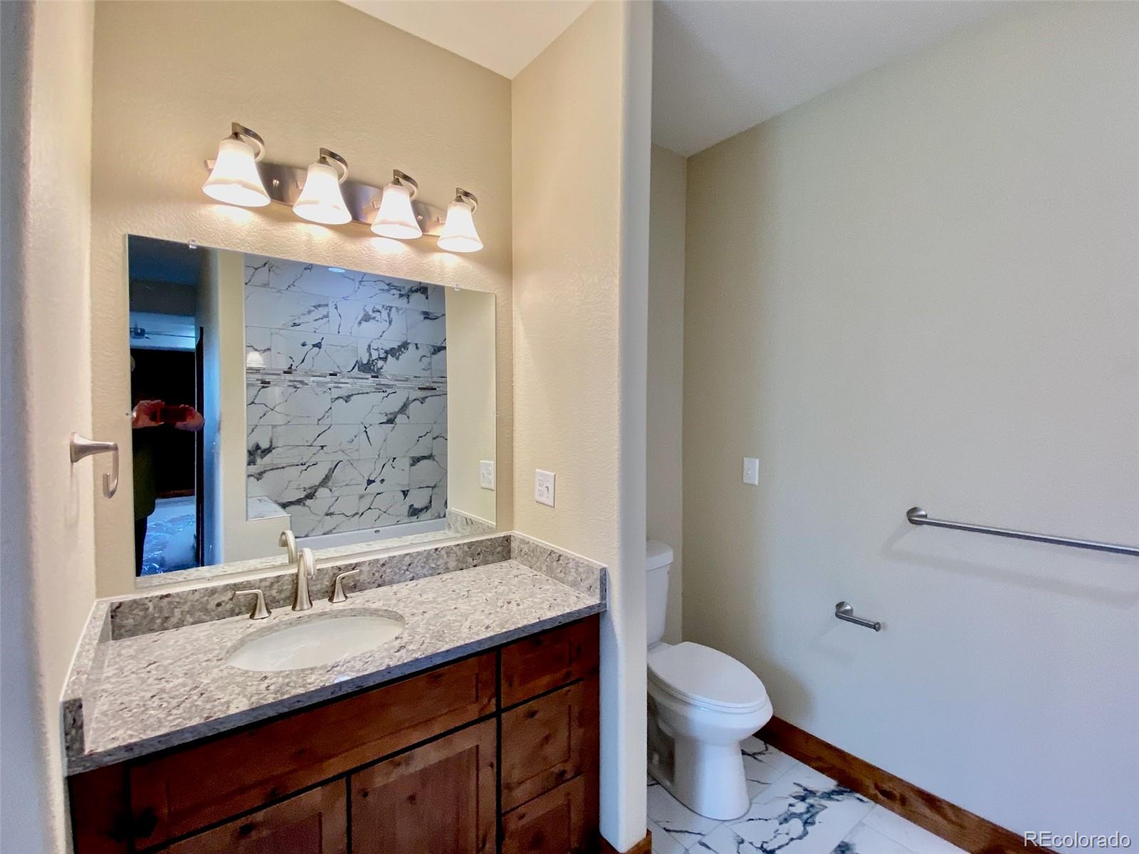 174 Chickadee Lane Bailey, CO 80421 - Photo 11 of 39 a bathroom with a granite countertop sink a toilet and a mirror
