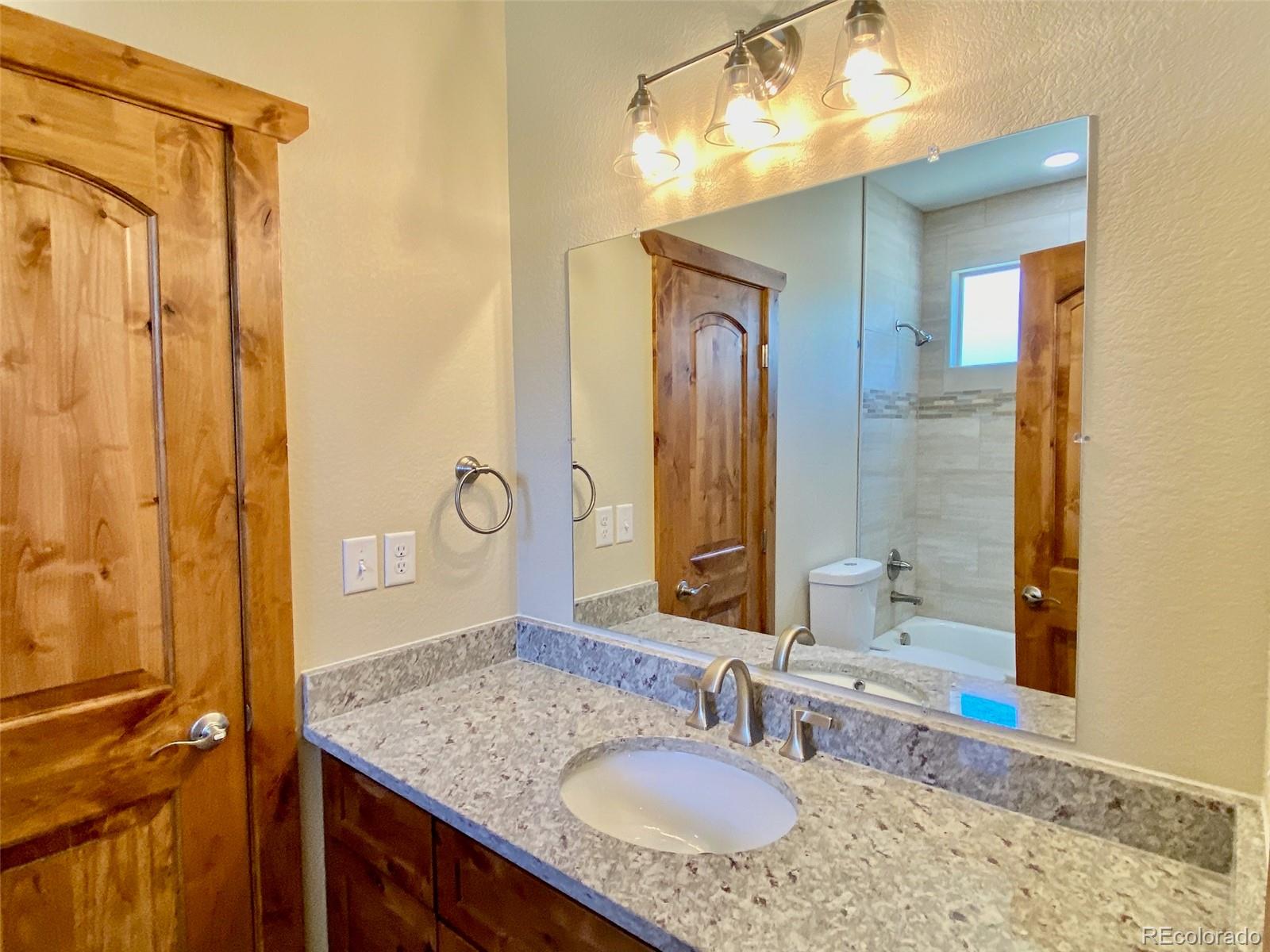 174 Chickadee Lane Bailey, CO 80421 - Photo 16 of 39 a bathroom with a granite countertop sink a mirror and a shower
