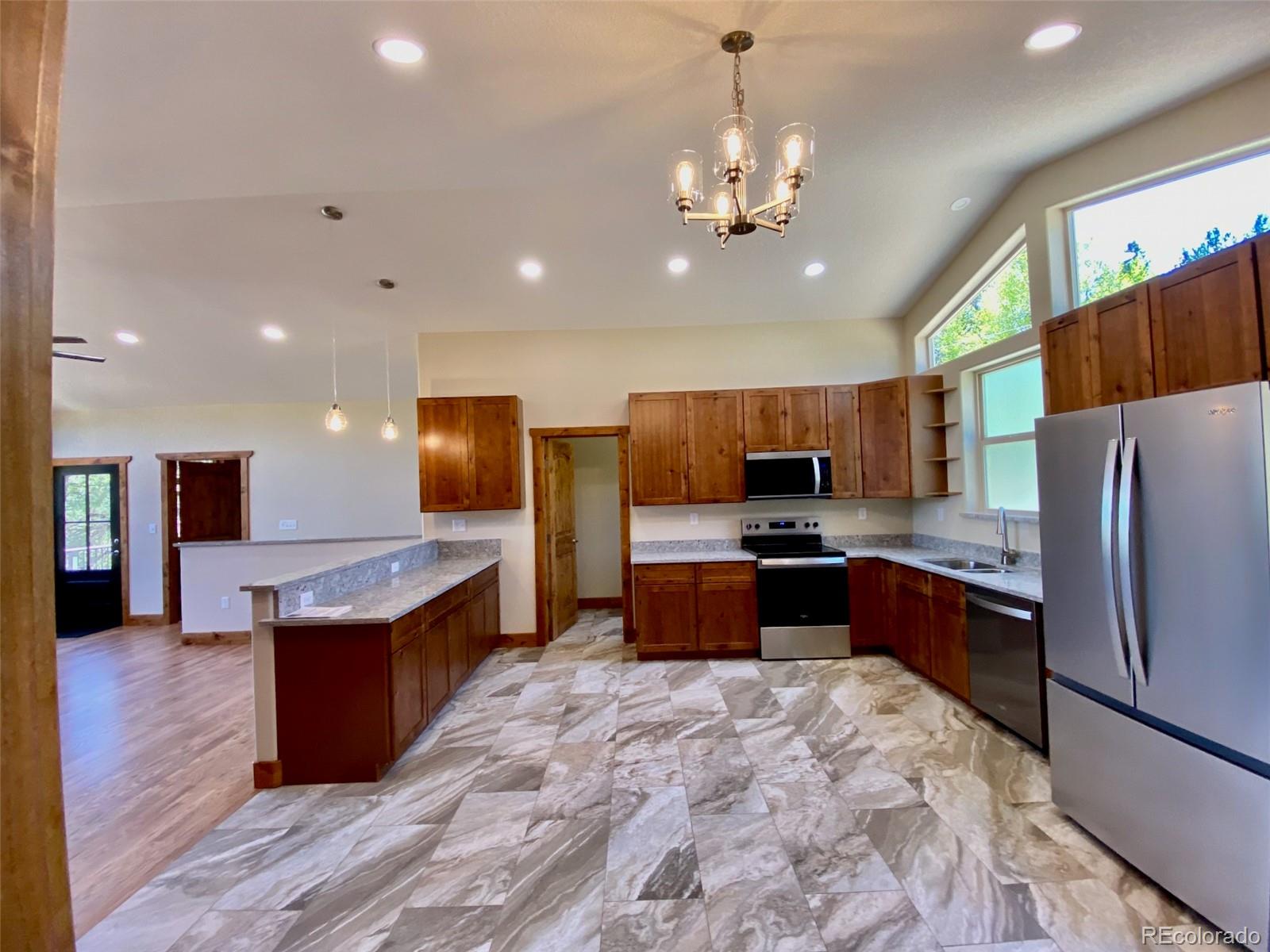 174 Chickadee Lane Bailey, CO 80421 - Photo 3 of 39 a kitchen with stainless steel appliances granite countertop a refrigerator a sink dishwasher a oven and a dining table with wooden floor