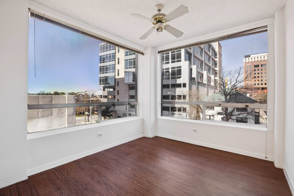 1212 Guadalupe Street, Unit 210 Austin, TX 78701 - Photo 1 of 12 Spare room featuring dark wood-style floors, a textured ceiling, a city view, and a ceiling fan