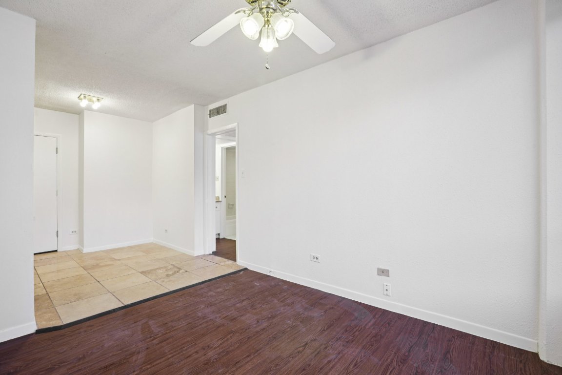 1212 Guadalupe Street, Unit 210 Austin, TX 78701 - Photo 11 of 12 Unfurnished room with wood finished floors, a ceiling fan, and a textured ceiling