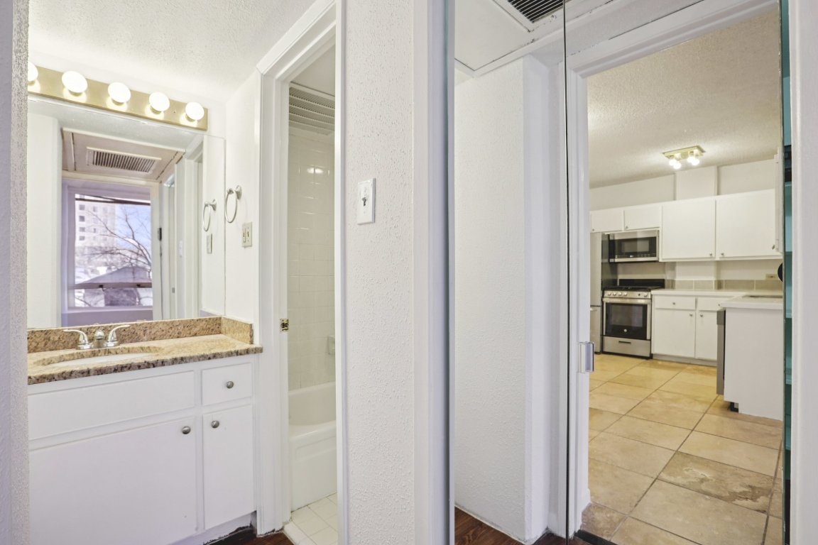 1212 Guadalupe Street, Unit 210 Austin, TX 78701 - Photo 4 of 12 Bathroom featuring a textured ceiling, a textured wall, vanity, and tub / shower combination