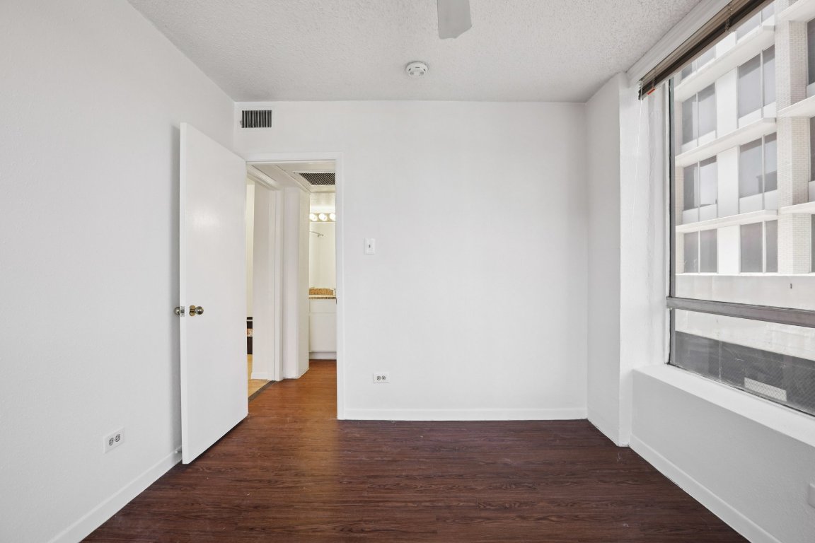 1212 Guadalupe Street, Unit 210 Austin, TX 78701 - Photo 6 of 12 Spare room featuring a textured ceiling and dark wood-style floors