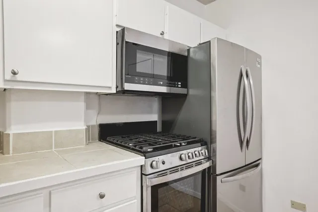 a kitchen with stainless steel appliances white cabinets and a stove top oven