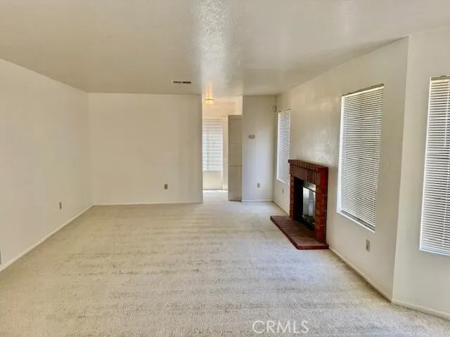 a view of an empty room with a fireplace and a window