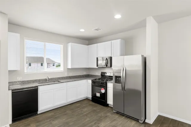 a kitchen with stainless steel appliances granite countertop a refrigerator a sink a stove and cabinets