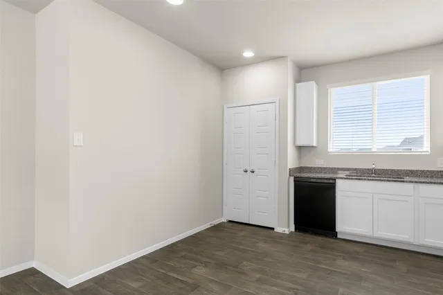 an empty room with wooden cabinet and windows