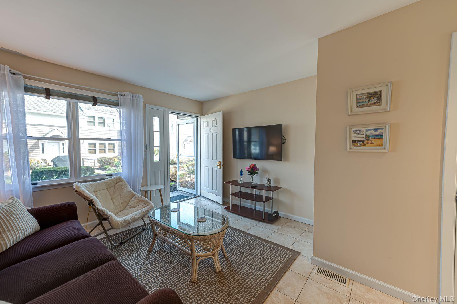 49 Canoe Place Road, Unit 212 Hampton Bays, NY 11946 - Photo 3 of 22 a living room with furniture and a flat screen tv