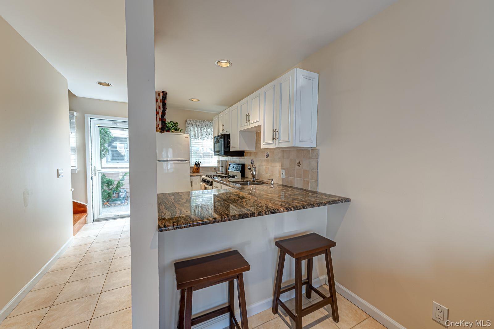 49 Canoe Place Road, Unit 212 Hampton Bays, NY 11946 - Photo 5 of 22 a kitchen with stainless steel appliances granite countertop a sink refrigerator and cabinets